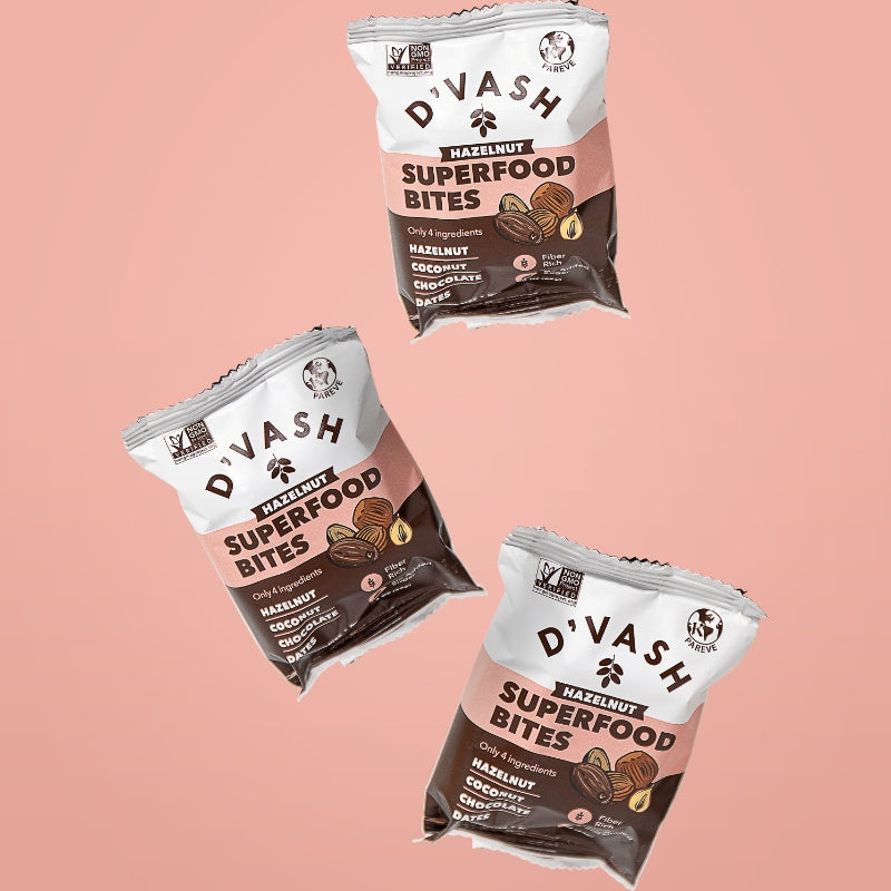 3 packs of hazelnut superfood bites suspended on pink background